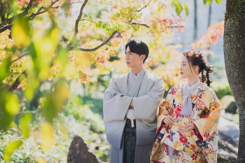 紅葉の中、色打掛と羽織袴で並ぶおふたり