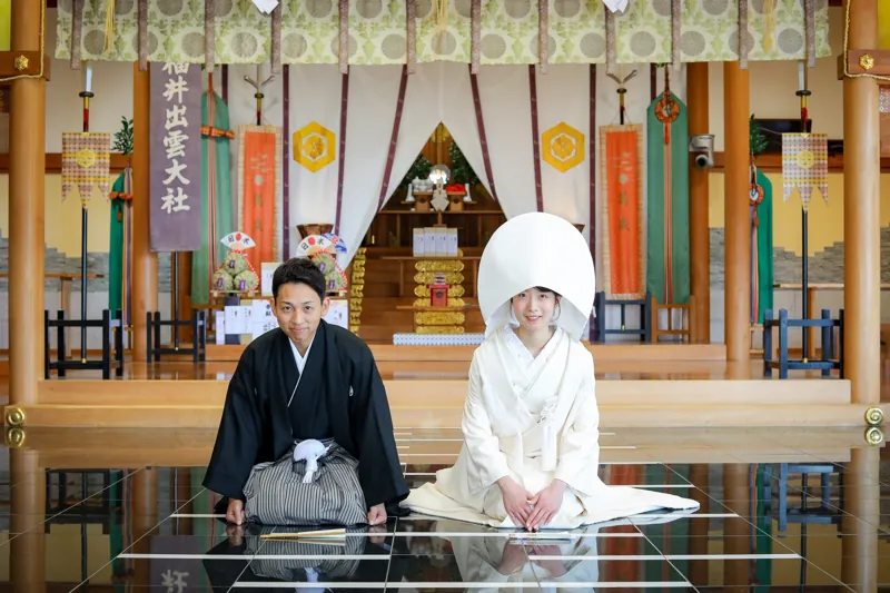 本殿で並んで座り、神前式に臨む白無垢と紋付袴のおふたり