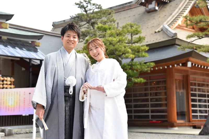 神社の社殿前で笑顔を見せるおふたり